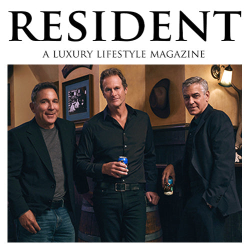 Three men holding cans in a dim bar setting beneath the headline RESIDENT A LUXURY LIFESTYLE MAGAZINE