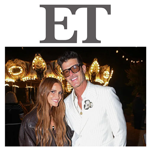 Two people smiling and posing in front of a lit carousel at an evening event