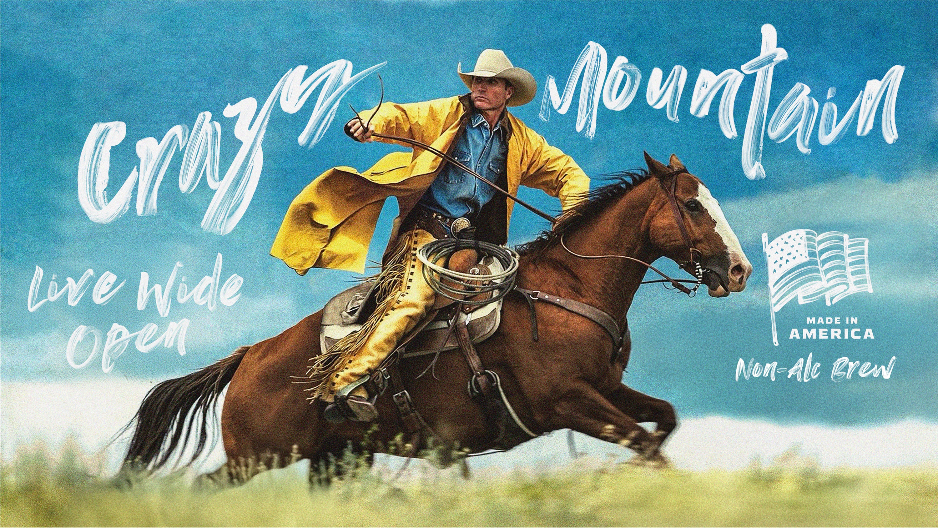 cowboy in yellow jacket looking over his right shoulder while riding a horse in a grassy open field with bridle in hand and lasso on his lap. Words Crazy Mountain appear in white brush strokes above his head, along with 'Live Wide Open' and 'Made in America Non-Alc Brew' below an American flag. 